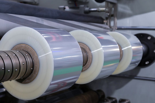 roll of plastic packaging film on the automatic packing machine in food product factory. industrial and technology concept.