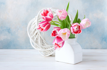 Bouquet of fresh pink tulips in vase on sky blue background. Concept for Valentine's day, wedding, engagement, mother's day, March 8. Close-up, selective focus, shallow depth of field