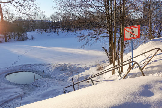 Ice hole in the lake in winter is equipped with a ladder for launching. prohibition sign with the inscription: do not go on the ice
