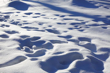 Snow drifts and footprints in the snow. Sunny day. Winter background.