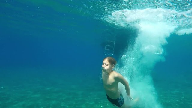 Teenage boy dives into the blue sea.  The boy swims in the Mediterranean sea under water. Slow motion. Mediterranean sea. Clean beautiful sea. 