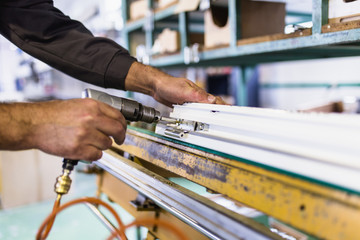 Factory for aluminum , wooden and PVC windows and doors production. Manual worker assembling PVC doors and windows. Selective focus.