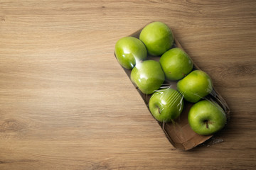 Opened package of green apples with one apple missing