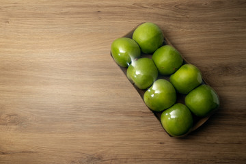 Eight packaged green apples on a wooden table
