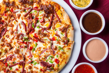 Delicious pizza with with sauces on the table. Food concept