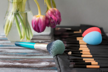Professional cosmetic brushes and sponges on a wooden table