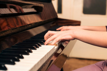 Fototapeta premium A teenage girl plays a piano at home, she prepares for a performance in front of her class at school. Side view