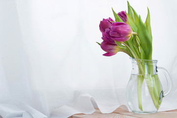 Beautiful bouquet of pink tulips flowers in a glass jug on white background. Place for text. Spring. holidays.