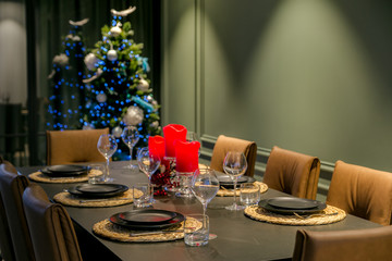 Christmas, holidays and table setting concept - glasses, dishes and red candles for a festive dinner at home