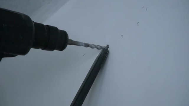 A Builder drills a hole in the wall