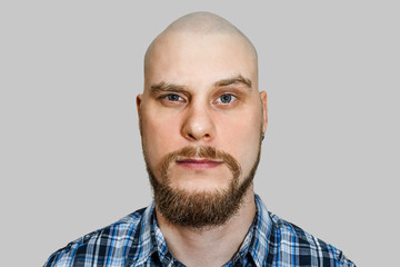 portrait of a serious, pensive, bald guy with a beard with narrowed eyes looking at the camera on an isolated background