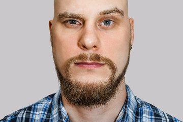 Obraz premium portrait of a serious, pensive, bald guy with a beard with narrowed eyes looking at the camera on an isolated background