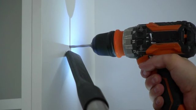 A Builder drills a hole in the wall