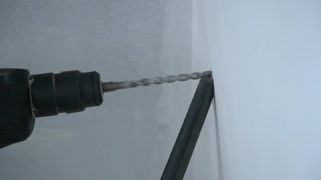 A Builder drills a hole in the wall