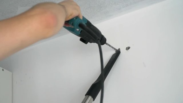 A Builder drills a hole in the wall