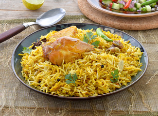 Chicken Biryani, a deleciously colorful rice dish filled with spicy marinated chicken  along with salad & raita.