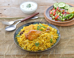Chicken Biryani, a deleciously colorful rice dish filled with spicy marinated chicken  along with salad & raita.