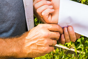 A groom putting on cuff-links as he gets dressed in his wedding day. Groom's suit