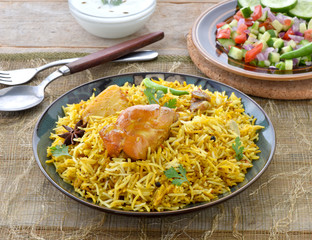 Chicken Biryani, a deleciously colorful rice dish filled with spicy marinated chicken  along with salad & raita.