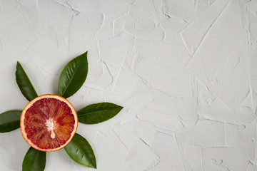 cut red blood orange with leaves similar to the sun on a light background. top view . the concept...
