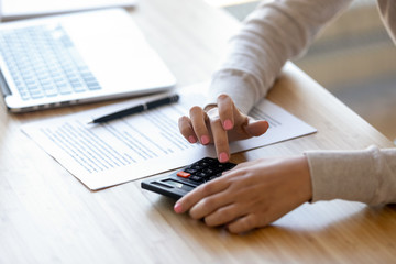 Close up young woman using calculator, calculating finance at workplace