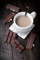 cup of coffee with pieces of chocolate on dark classic wood