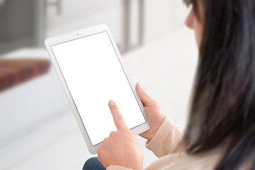 Woman use white tablet with isolated screen form mockup, app or web site presentation. View over shoulder. Home interior in background.
