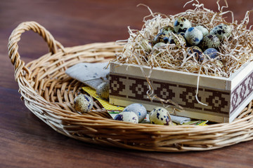 Eggs of quails in a basket on a straw substrate. Spring day. Festive easter mood.