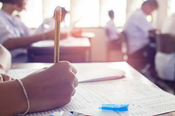 Close up to hand of student is taking exam and writing answer in classroom for education test...