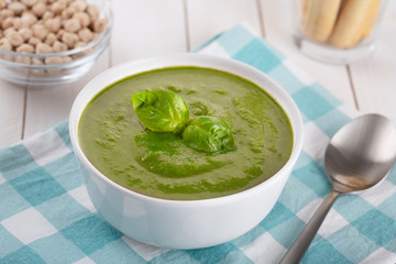 Green cream soup of spinach and chickpeas on concrete wood background