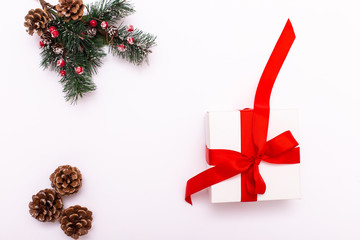 Creative frame made of Christmas fir branches on white paper background with red decoration, gift boxes. X-mas and New Year theme. Flat lay, top view