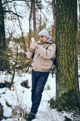 Senior man wearing stylish winter clothes and backpack using mobile phone