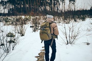 Naklejka premium Senior man wearing stylish winter clothes and backpack traveling in a forest