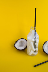 Detox water with coconut in the glass bottle  on the yellow  background.Copy space.