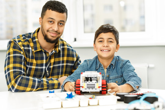 Young boy and his father building a robot together