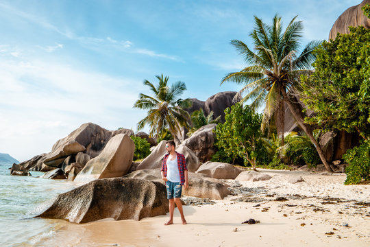young men on tropical beach with palm tree, white beach man walking Seychelles Island, tanning men on tropical vacation