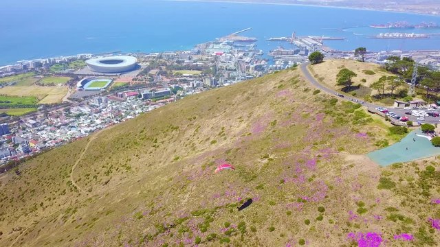 Drone aerial over paragliding and paragliders with the downtown city of Cape Town, South Africa, in background.