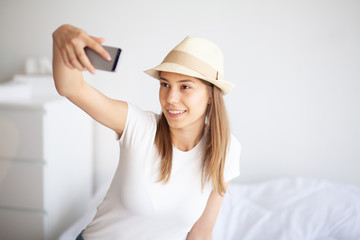 Woman legs raised up on the baggage, Young woman at home laying in bed. The white bedroom