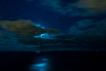 Clouds and stars over the ocean at moonlight