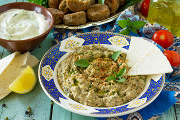 Arabic cuisine. Fresh homemade creamy mung hummus with spicy, falafel, sour cream sauce on a wooden kitchen table. Ramadan food.