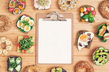 Stylish and tasty composition of vegan and vegetarian breakfast. Planning your healthy diet. Organic vegetables and sandwiches on the wooden table. Mock up menu concept. Fresh and healthy meal. 