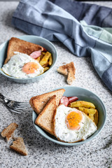 Breakfast with French fries, fried egg, sausage and toast on the table