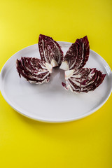 Red radish in the white plate on the yellow background