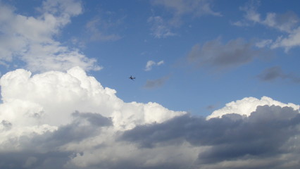 Blue sky with white clouds and a plane