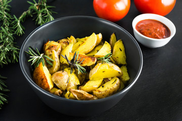Spicy baked potatoes with rosemary and tomato sauce. Vegetarian food background.