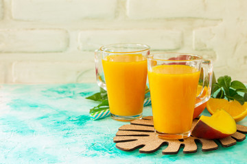 Concept of vegetarian food, fresh vitamins. Refreshing summer mango and citrus freshly squeezed juice on stone table. Copy space.