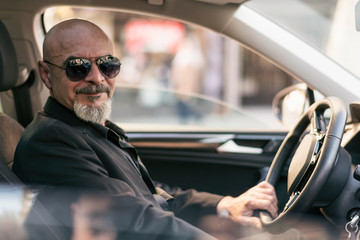 Senior 60s man driving suv luxury car in close up image