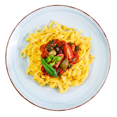 Tagliatelle with tomato sauce, olives, capern and basil leaves on rustic glazed clay plate - isolated on white background