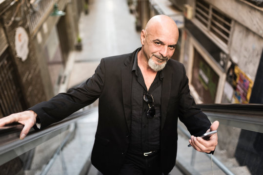 Senior business man in scalator with smartphone