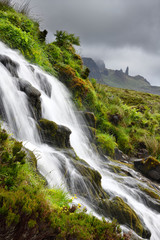 Fototapeta na wymiar Bride's Veil WaterFalls to Loch Leathan at The Storr with Old Man of Storr peak in clouds on Isle of Skye Inner Hebrides Scotland UK